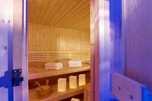 Innenansicht der Sauna im Astir Beach Hotel auf Kreta mit Holzbänken, weißen Handtüchern und dekorativen Laternen.