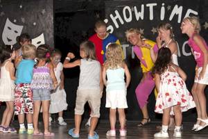 Gruppe von Kindern und zwei Erwachsenen in Showkostümen auf einer Bühne des Astir Beach Hotels in Kreta.