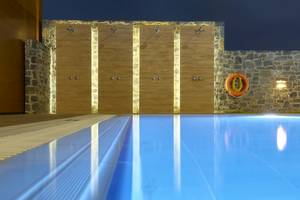 Ein leerer Pool im Astir Beach Hotel in Kreta mit Steinwänden und Duschen.