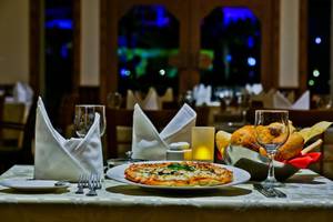 Im Charmillion Club Aqua Park ein Tisch mit einer Pizza, Gläsern und Brötchen.