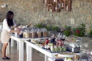Frühstücksbuffet im Rocabella Mykonos Art Hotel & Spa mit einer Frau, die Essen serviert.