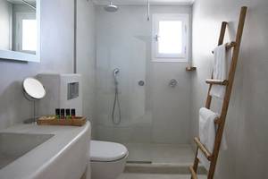 Badezimmer im Rocabella Mykonos Art Hotel mit Glasdusche, Toilette, Waschbecken und Holzleiter.