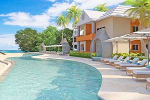 Außenpoolbereich des Coral Level at Iberostar Selection Bávaro mit Sonnenliegen und Sonnenschirmen.