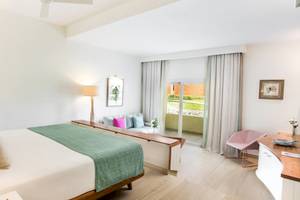 Schlafzimmer im Coral Level at Iberostar Selection Bávaro mit einem Bett, Lampen und Möbeln.