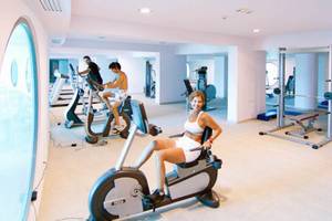 Fitnesscenter im Kresten Royal Euphoria Resort mit einer Frau auf einem Radtrainer.