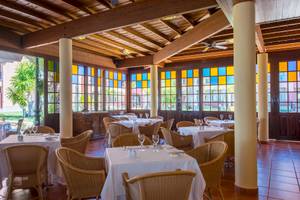 Innenansicht des Restaurants im Iberostar Selection Anthelia Hotel mit bunten Glasfenstern und Holzmöbeln.