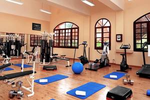 Fitness Center im Jaz Makadi Oasis Resort & Club mit Geräten und Yoga-Matten auf Holzboden.