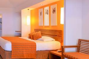 Innenansicht eines Hotelzimmers im Adaaran Select Hudhuran Fushi, mit Bett, Fernseher und Möbeln.