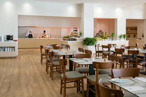 Restaurant im Louis Paphos Breeze Hotel mit Köchen und gedeckten Tischen.