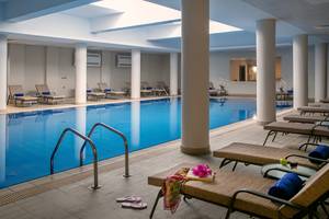 Innenpool des Louis Paphos Breeze Hotels mit Lounge-Liegestühlen und Dekoration.