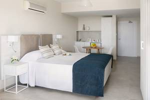 Innenansicht eines Zimmers im Louis Paphos Breeze Hotel mit einem Bett, Tisch, und einer kleinen Küche.