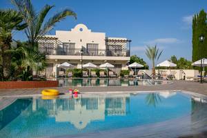 Außenansicht des Louis Paphos Breeze Hotels mit Swimmingpool, Sonnenliegen und Schirmen