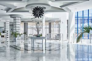 Lobby des Rodos Princess Beach Hotels mit Marmorboden, modernen Möbeln und Pflanzen.