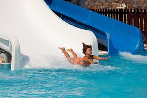 Mädchen rutscht von einer weißen Rutsche in den Pool im Rodos Princess Beach Hotel.