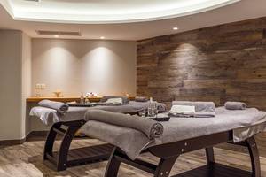 Massagebereich im Rodos Princess Beach Hotel mit zwei Massagetischen und Holzwänden.