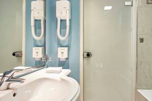 Badezimmer im Esperides Beach Resort mit Waschbecken, Spiegel und Dusche.