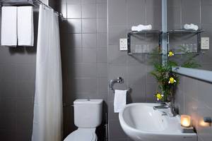 Badezimmer im Esperides Beach Resort mit grauen Fliesen, einer Toilette, einem Waschbecken und Handtüchern