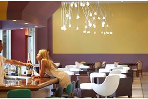Ein Mann und eine Frau an der Bar im Esperides Beach Resort, beide mit Getränken, das Hotel im Hintergrund.