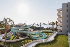 Wasserrutsche im Freien neben einem Hotelgebäude mit Blick auf das Meer.