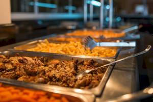 Buffet-Tisch im Astir Palace Hotel mit verschiedenen Gerichten wie Fleisch, Reis und Pommes.