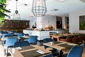 Innenansicht des Restaurants des NH Amsterdam Centre Hotels mit blauen Stühlen und Tischen.