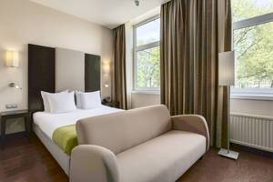 Ein Zimmer im NH Amsterdam Centre Hotel mit einem Bett, einer Couch und Fenstern.