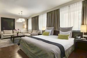 Schlafzimmer im NH Amsterdam Centre Hotel mit großem Bett, Sofas und Nachttischen.