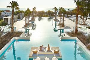 Poolbereich des Grecotel Lux Me Dama Dama Hotels mit Paar, das sich entspannt.