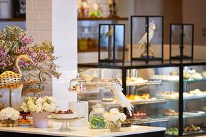 Empfangsbereich des Grecotel Lux Me Dama Dama Hotel mit Blumen, Figuren und Kuchen