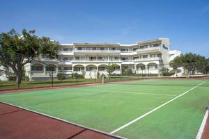 Tennisplatz vor dem Niriides Beach Hotel, einem weißen Gebäude mit vielen Fenstern.