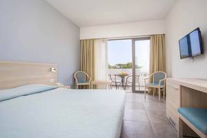 Zimmer im Niriides Beach Hotel mit Bett, Schreibtisch und Balkon