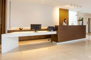 Empfangsbereich des Niriides Beach Hotels mit weißer Theke und einer Dame am Telefon.