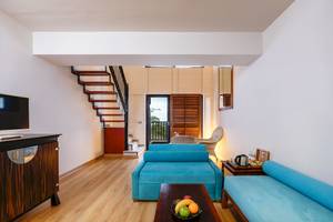 Wohnzimmer im Asteria Family Resort Belek mit blauen Sofas, Tisch, Fernseher und Treppe.