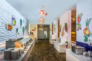 Innenbereich des Restaurants im Asteria Family Resort Belek mit farbenfrohen Wanddekorationen und Holzboden.