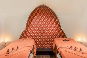 Behandlungsraum im Asteria Family Resort Belek mit zwei orangefarbenen Betten und einer aufwendigen Wand.