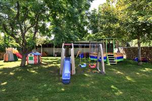 Ein Kinderspielplatz im Freien im Su Hotel mit Rutschen, Schaukeln und Klettergerüst.