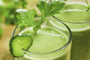 Zwei Gläser mit grünem Smoothie und Gurke, das Hotel Anantara Rasananda Koh Phangan Villas im Hintergrund