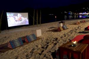 Strandkino-Nachtveranstaltung im Anantara Rasananda Koh Phangan Villas mit Leinwand und roten Kissen.