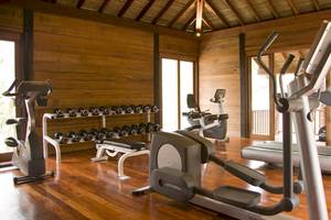 Fitnesscenter im Anantara Rasananda Koh Phangan Villas mit verschiedenen Geräten und Hanteln.