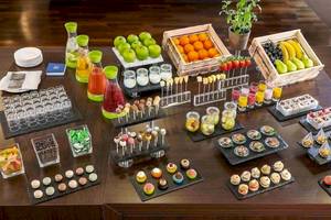 Buffet-Tisch im NH Hamburg Altona mit verschiedenen Desserts, Früchten und Getränken.