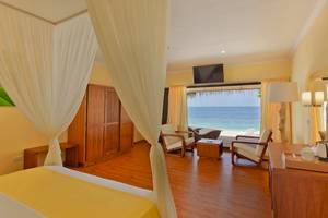 Hotelzimmer mit Meerblick, komplett mit Bett, Möbeln, Fernseher und Aussicht auf den Strand.