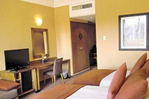 Doppelzimmer im Atlas Medina & Spa Hotel mit zwei Betten, Schreibtisch, Fernseher und Dekor.