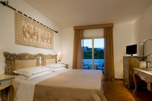 Hotelzimmer im Colonna Grand Hotel Capo Testa mit einem Bett, Fernseher und Balkon.