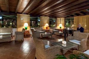 Innenansicht der Lobby des Colonna Grand Hotel Capo Testa mit Möbeln und Lampen