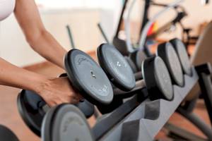 Eine Person hebt eine Hantel in einem Fitnessstudio.