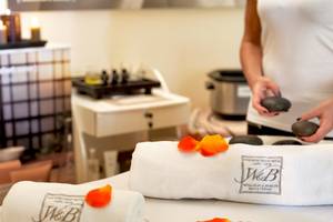 Spa-Behandlung im Colonna Grand Hotel Capo Testa mit weißen Handtüchern und Rosenblättern.