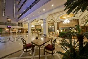 Foyer im Aydinbey Kings Palace & Spa Hotel mit Holztisch, Kronleuchtern und Pflanzen.