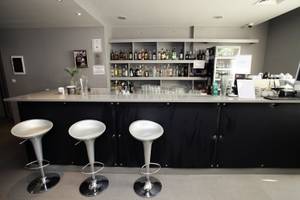 Die Bar im Gladiola Star Hotel mit Barhockern und einer Theke voller Getränke.