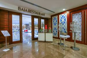 Der Eingangsbereich des Baia Restaurants mit Holztüren und einer Theke mit Weinkühlern.