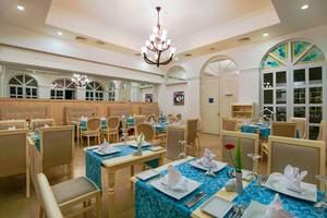 Innenansicht des Restaurants im Baia Lara Hotel mit gedeckten Tischen und Stühlen.